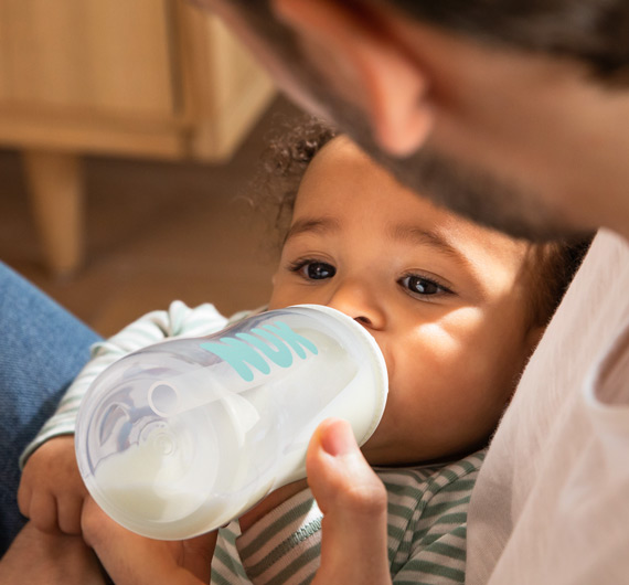 Vater füttert Kind mit NUK Anti-Colic Babyflasche